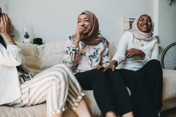 Three friends talking together sitting on the sofa at home
