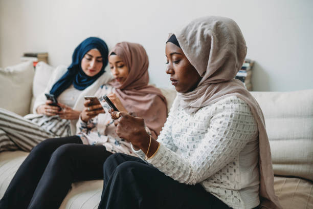 istock Arab friends using mobile phones sitting on the sofa at home 1158438319