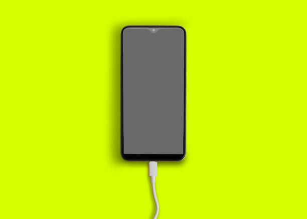 istock Smart phone battery charging with cable on yellow background 1158438525