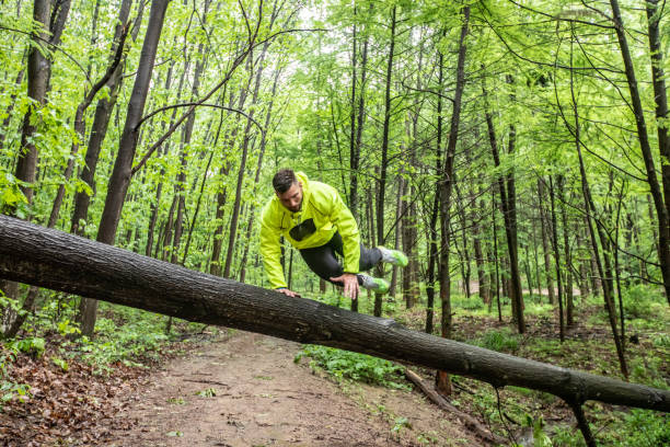 istock Adult Man Runner Jumping Across a Tree Trunk in Forest 1158441614