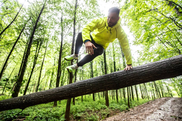 悪天候で森の中を走る大人の男 - obstacle course ストックフォトと画像