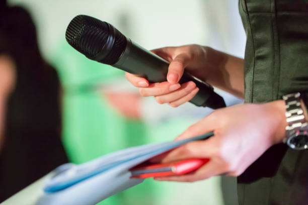 istock Female hands are holding a microphone on the stage 1158442916