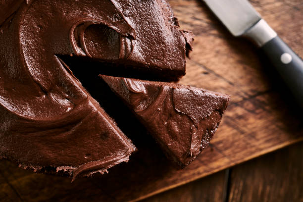 geschnittener schokoladenkuchen gegen eine rustikale holzoberfläche. - chocolate cake stock-fotos und bilder