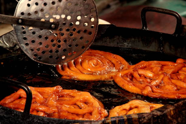 istock Jalebi sweet dish being fried in sugar syrup in a large container. 1158449046