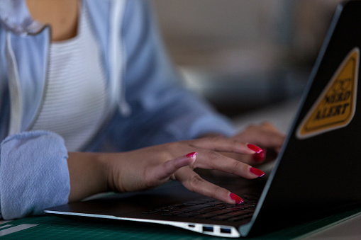 A close up photo of a female typing on a laptop.