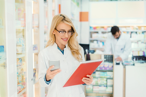 young pharmacist checking medication details, pharmacist using tablet