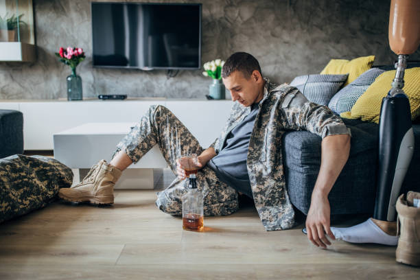 istock Depressed soldier with amputee leg drinking alcohol 1158453430