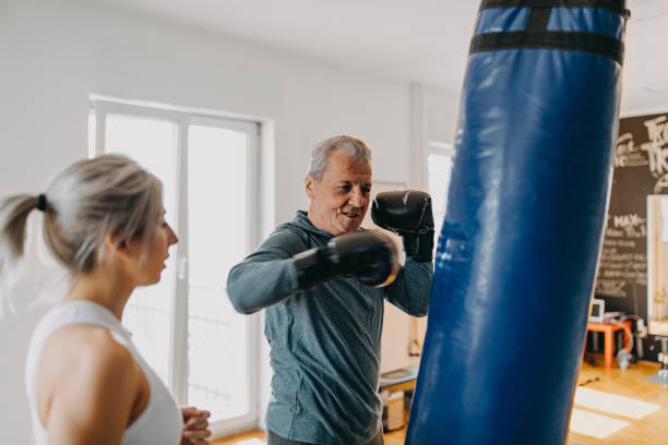 Senior man exercising with his personal trainer Senior man exercising with his personal trainer old man boxing stock pictures, royalty-free photos & images