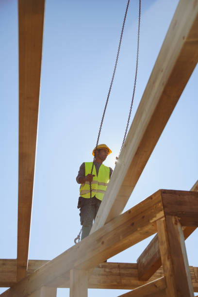 istock Construction worker standing on a wooden house construction site 1158455882