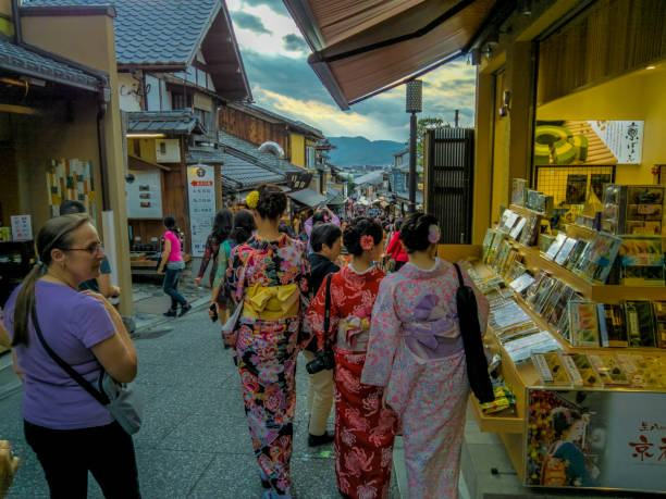 Kyoto, Japan - May 16, 2019: Shops and tourists near the busy entrance to Kiyomizu-dera, Buddhist temple in eastern Kyoto. Women in kimonos visiting the temple are depicted here.