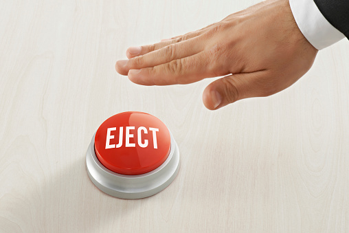 Businessman reaching red ‘eject' button.