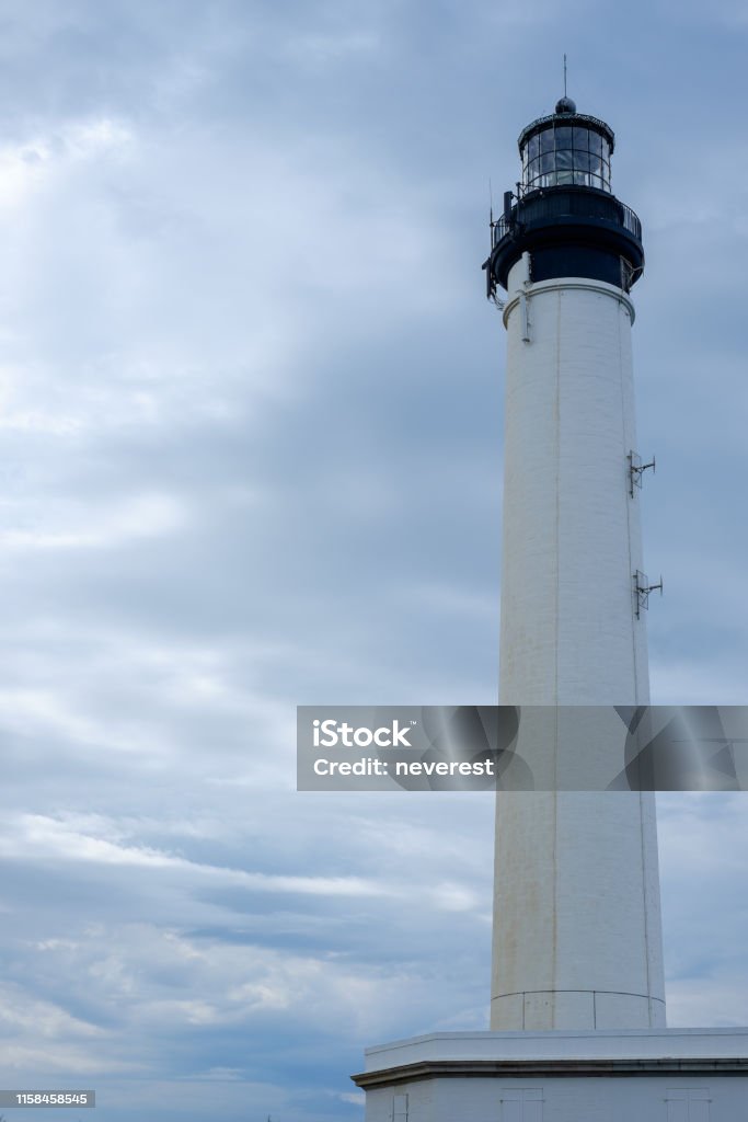 White lighthouse under an overcast sky Tall white lighthouse under an overcast sky Black Color Stock Photo