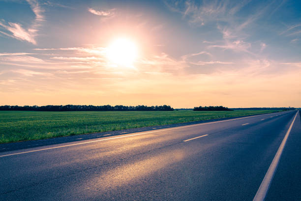 Empty asphalt highway against the bright sun at sunset. Toned image