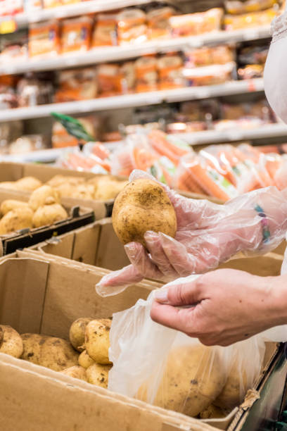istock Woman in Hypermarket Choosing Fresh Raw Potatoes 1158462444