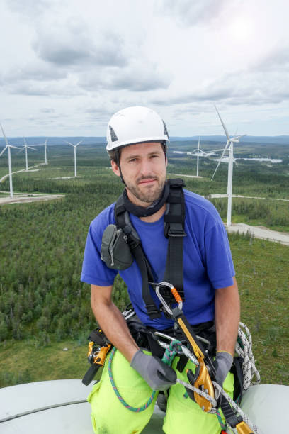 istock Rope access technician siting on wind turbine with wind farm behind 1158465075