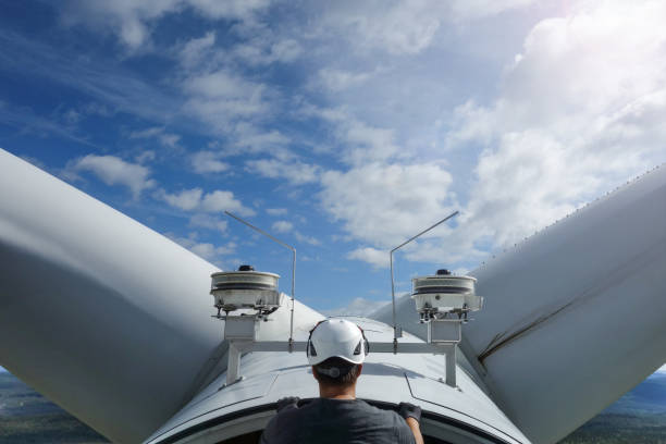 tecnico operaio su turbina eolica in alto tra le pale - working windmill foto e immagini stock