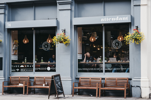 London, UK - June 15, 2019: View through the window of people inside Attendant cafe and bar in Shoreditch, a trendy area of Londons East End that is home to an array of markets, bars and restaurants.