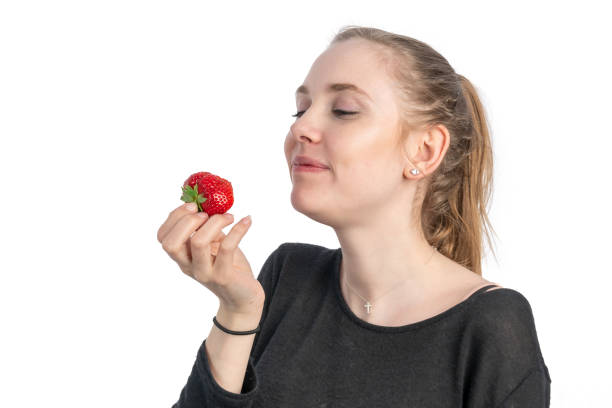 A young woman enjoys eating a strawberry
