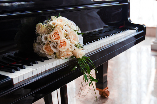delicate wedding bouquet of roses lies on the keys of the grand piano