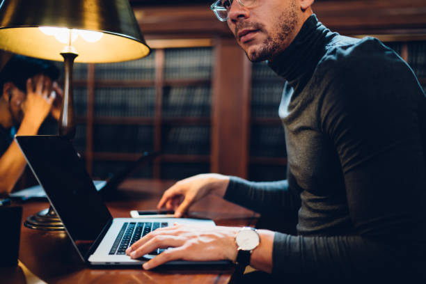 istock Young male scientist thinking on project making research in university library with wifi access, cropped image of professional journalist downloading files from book archive pondering on review 1158476151