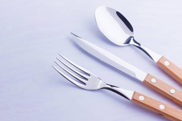 istock Set of cutlery: knife, fork, spoon on white background. Table setting. Concept of cutlery with wooden handles - laconic minimalistic design. Top view 1158476346