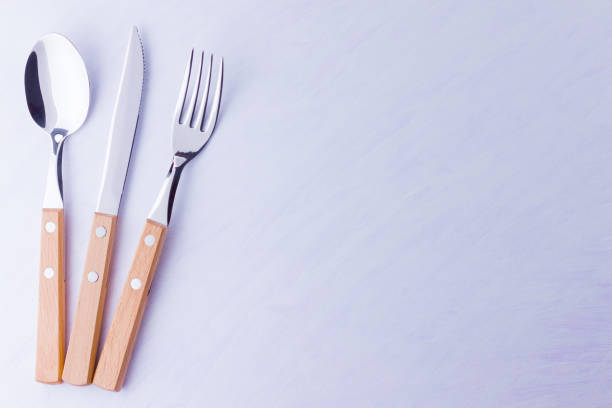 istock Set of cutlery: knife, fork, spoon on white background. Table setting. Concept of cutlery with wooden handles - laconic minimalistic design. Top view 1158476377