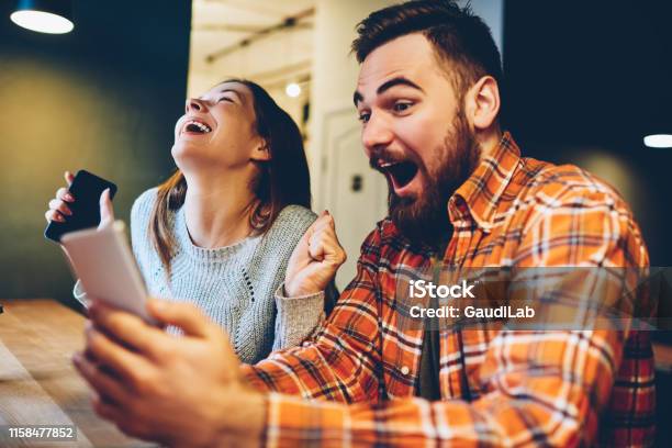 Excited Male And Female Hipsters Rejoice In Winning An Internet Lottery Made Bets On Website On Modern Smartphonehappy Couple In Love Celebrating Victory In Online Competitions Enjoying Success Stock Photo - Download Image Now