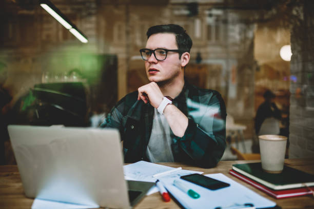 istock Serious male student in eyewear for vision protection pondering during e learning on courses, pensive man doing remote job via laptop computer in cafe analyzing information for project looking away 1158478870