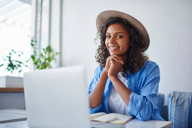 istock Portrait of skilled african american female student using laptop computer for learning and browsing information,cheerful dark skinned hipster girl looking at camera while updating software on netbook 1158480827