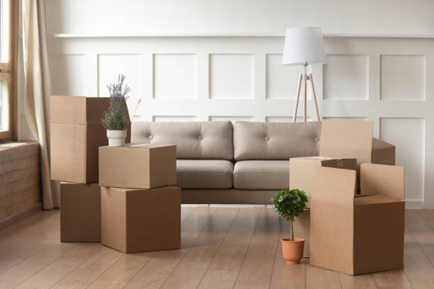 Moving day concept, cardboard boxes in modern house living room Moving day concept, cardboard carton boxes stack with household belongings in modern house living room, packed containers on floor in new home, relocation, renovation, removals and delivery service company relocation stock pictures, royalty-free photos & images