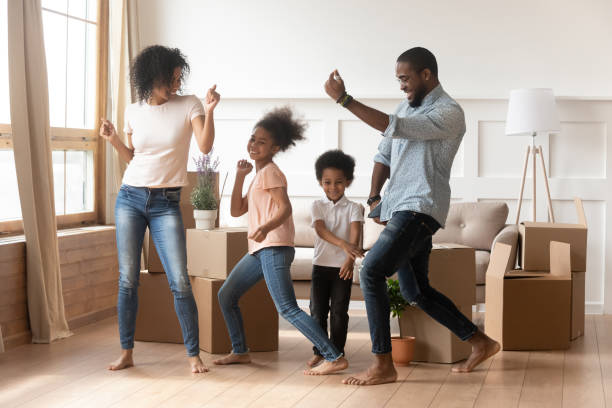 felices padres afroamericanos y niños bailando celebrando el día de la mudanza - happy time fotografías e imágenes de stock