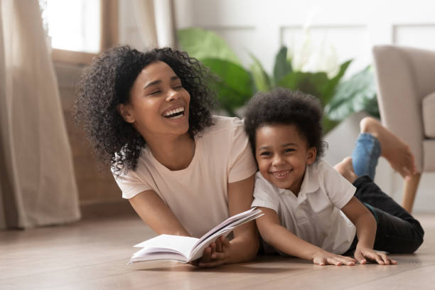 livre de lecture de mère africaine riant avec le fils d'enfant à la maison - family reading african descent book photos et images de collection