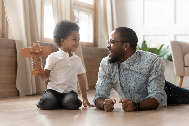 istock Cute african kid boy holding toy plane play with dad 1158481692
