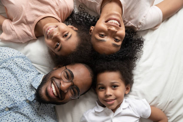 istock Happy african family looking at camera on bed, top view 1158481708