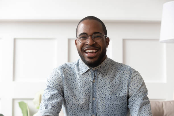 happy black man video calling looking at camera at home - looking in camera imagens e fotografias de stock