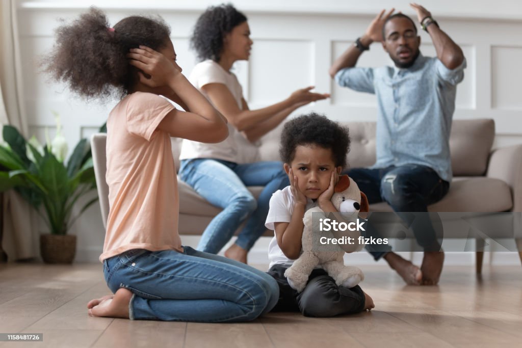 Upset african kids closing ears hurt by parents fighting Upset african kids closing ears hurt by parents fighting arguing at home, sad stressed little innocent children suffer from family problems conflicts, unhappy mom dad shouting quarreling divorcing Family Stock Photo