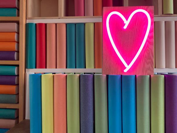 istock Books shelves packed with generic colorful books and neon heart shape 1158481801