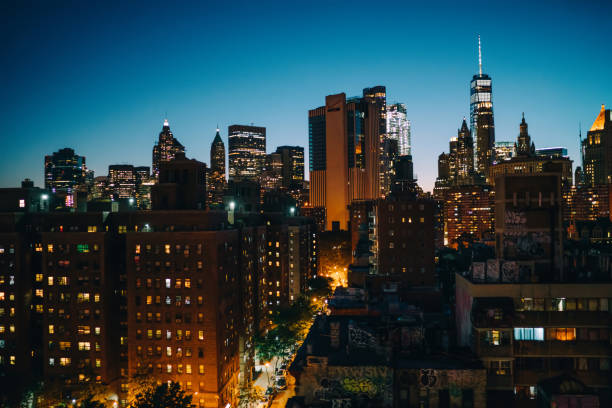 istock Urban setting at dusk with tall architecture construction shining with window lights; New York big city life in evening with skyscrapers and towers for rental real estate in district of megalopolis 1158482057