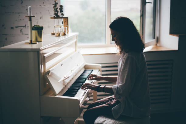 Girlfriend spend time. Women playing on piano in bright apartment. Side view young girl making music exercise near at background window. C chord photos stock pictures, royalty-free photos & images