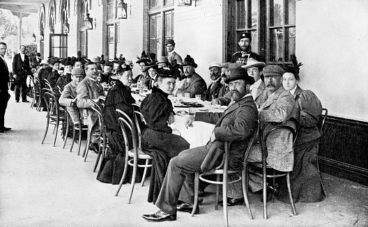 Large group of men and women sitting at tables at a train station in Saint Petersburg, Russia. The Russian Empire era (circa 19th century). Vintage halftone photo etching circa late 19th century.