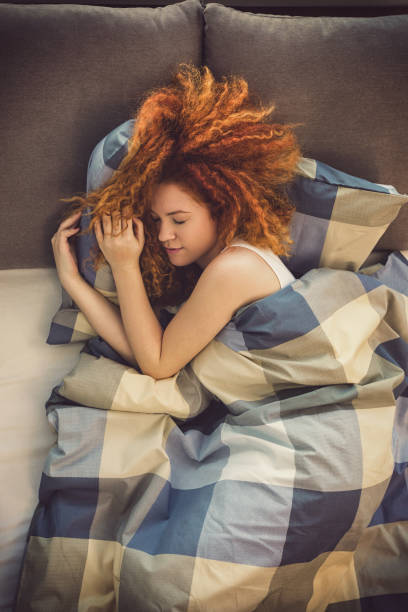 verticale d'une belle jeune fille dormant dans le lit - waking up women bedding underwear photos et images de collection