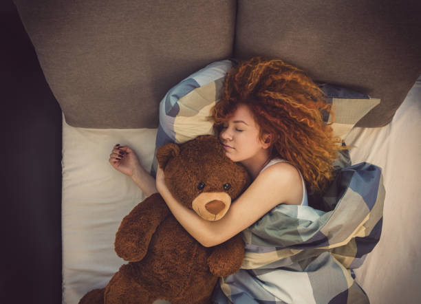 Portrait of a beautiful young girl with teddy bear sleeping in bed at home Portrait of a young beautiful redhead girl with teddy bear sleeping in bed at home stuffed toy stock pictures, royalty-free photos & images