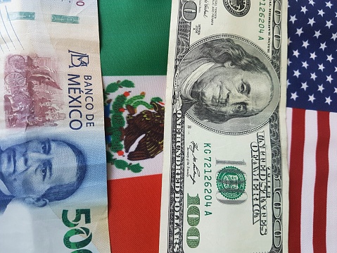 The flags of Mexico and the US, each with a paper bill.