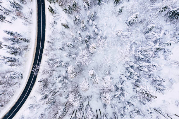 istock Curvy windy road in snow covered forest, top down aerial view. Winter landscape. 1158489627