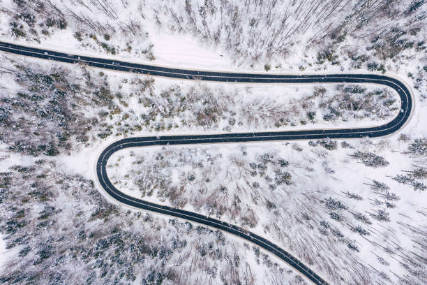 istock Curvy windy road in snow covered forest, top down aerial view. Winter landscape. 1158489629