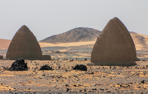 Islamic domed tombs and shrines (called qubba) next to the abandoned town of Old Dongola in the Nubian desert in northern Sudan. Old Dongola is a deserted medival Nubian town on the banks of the Nile River and the ancient capital of the Mankurian state. The Nubian Desert is in the eastern region of the Sahara Desert, between the Nile and the Red Sea. The native inhabitants of the area are the Nubians, descendants of the ancient Nubian civilizations also known and the Black Pharaohs.