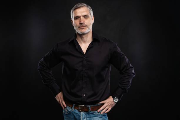 istock Middle-aged good looking man posing in front of a black background with copy space. 1158490659