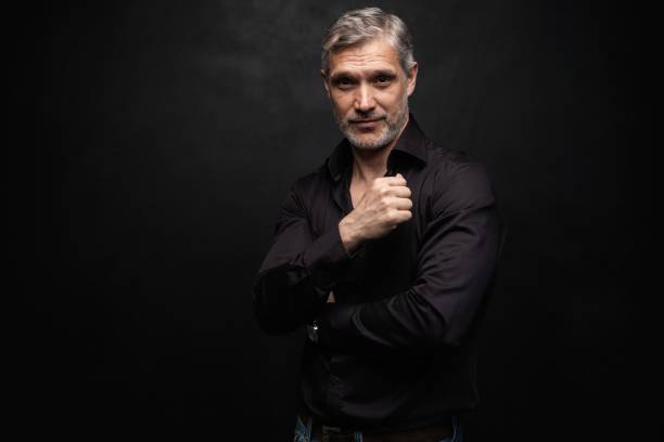 istock Middle-aged good looking man posing in front of a black background with copy space. 1158490660