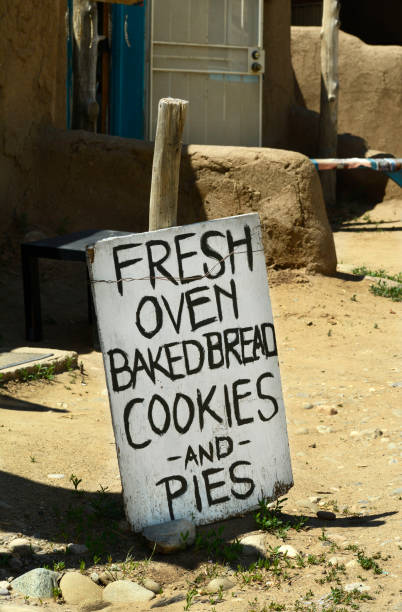 Native American cafe at Taos Pueblo near Taos, New Mexico TAOS, NEW MEXICO- MAY 15, 2019:  A sign outside a souvenir and snack shop at Taos Pueblo, an ancient Native-American pueblo near Taos, New Mexico USA,  advertises oven-backed bread, cookies and pies made by American Indians. adobe oven stock pictures, royalty-free photos & images