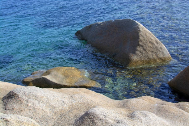 Tourists and bathers on the sand and rock beaches typical of Sardinia.